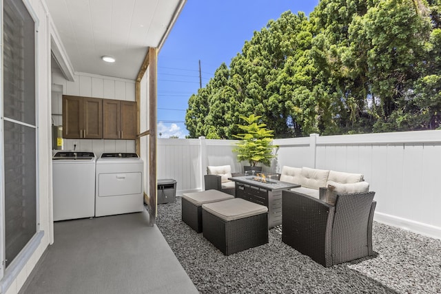 view of patio / terrace featuring an outdoor living space with a fire pit, a fenced backyard, washer and clothes dryer, and area for grilling