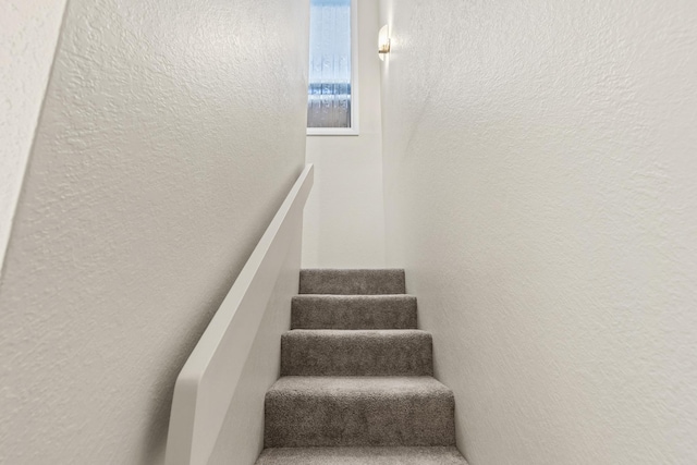 staircase featuring a textured wall