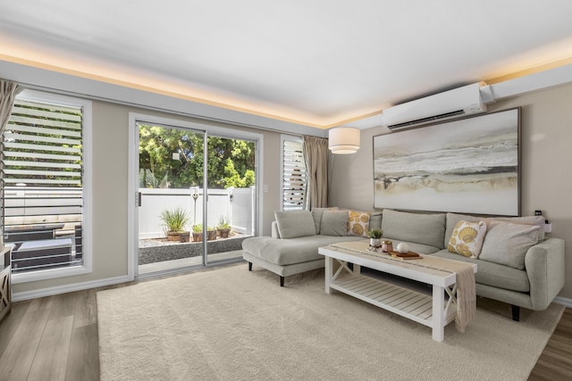 living room with a wall mounted AC and wood finished floors