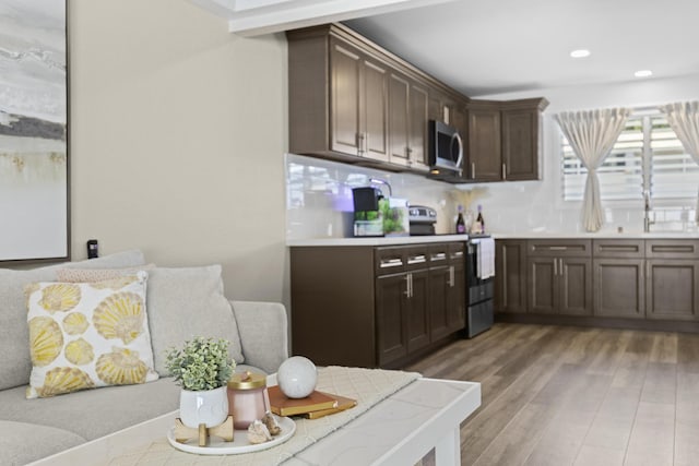 kitchen with light wood-style flooring, recessed lighting, light countertops, appliances with stainless steel finishes, and dark brown cabinets