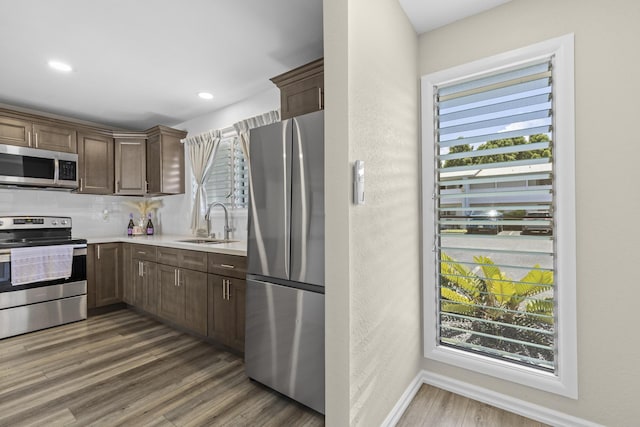 kitchen featuring a sink, stainless steel appliances, dark wood-type flooring, and light countertops