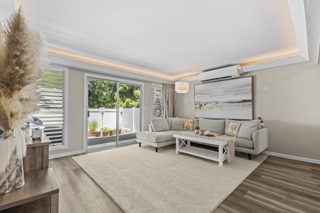 living room with a wall mounted AC, wood finished floors, and baseboards