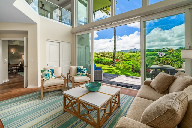 living room featuring a healthy amount of sunlight, hardwood / wood-style flooring, and a towering ceiling