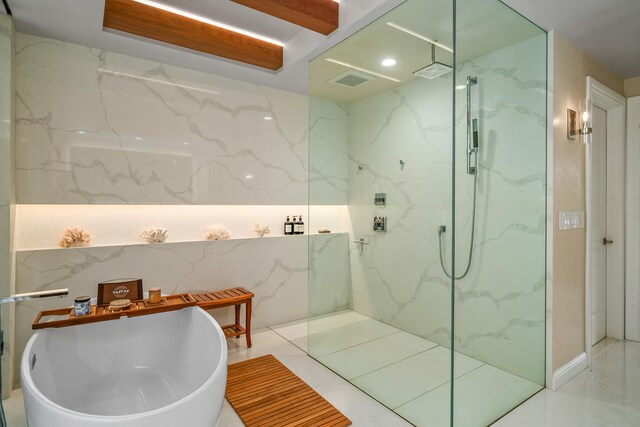 bathroom with independent shower and bath, tile patterned flooring, and tile walls