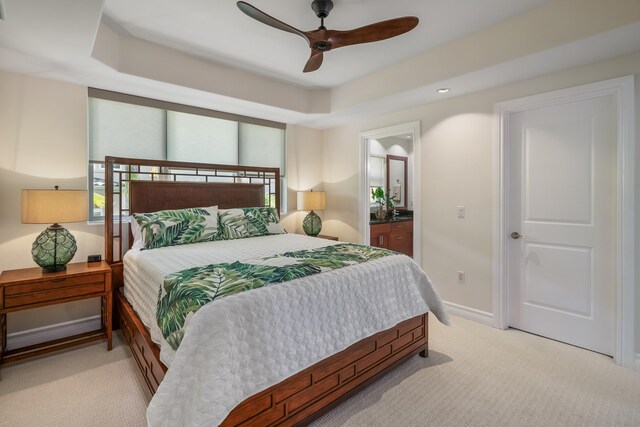 carpeted bedroom featuring connected bathroom, ceiling fan, and a raised ceiling