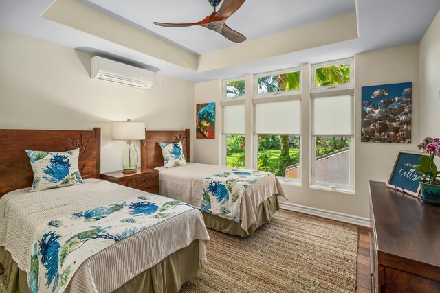 bedroom with an AC wall unit, multiple windows, hardwood / wood-style floors, and ceiling fan