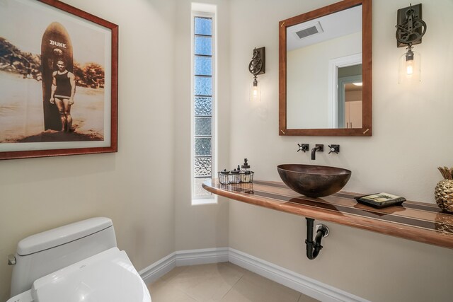 bathroom with sink, toilet, and tile patterned flooring