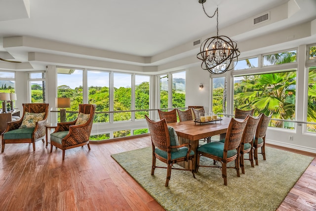 dining area featuring light hardwood / wood-style floors, an inviting chandelier, and a tray ceiling