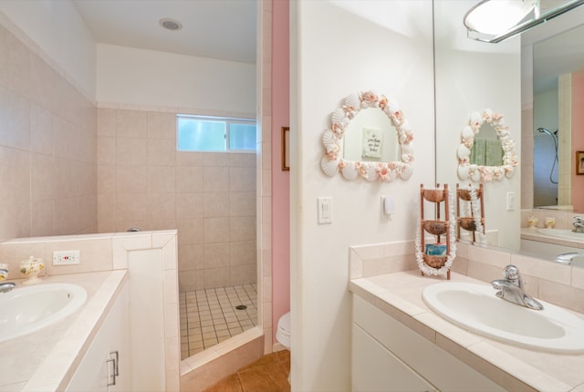 bathroom featuring tile patterned floors, toilet, vanity, and a tile shower