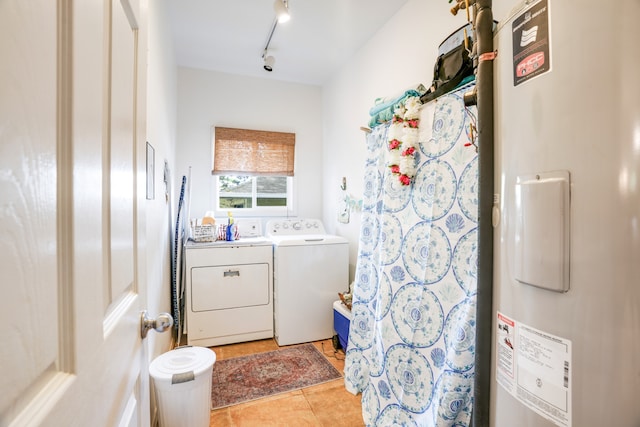 clothes washing area featuring electric water heater, washer and dryer, light tile patterned floors, and track lighting