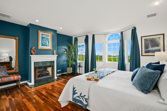 bedroom featuring hardwood / wood-style flooring and a high end fireplace