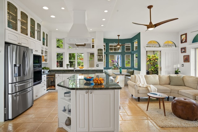 kitchen with light tile patterned flooring, appliances with stainless steel finishes, a center island, ceiling fan, and white cabinets