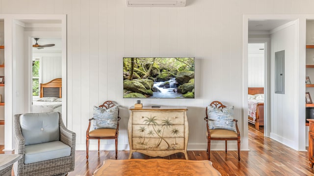 living area with wood-type flooring, electric panel, and an AC wall unit