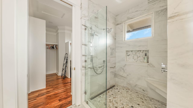 full bathroom with ornamental molding, a spacious closet, a marble finish shower, and wood finished floors