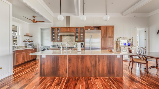 kitchen featuring stainless steel built in refrigerator, brown cabinets, a sink, and beam ceiling