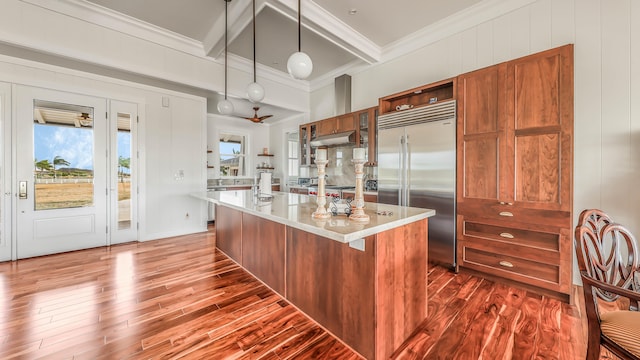 kitchen featuring stainless steel appliances, brown cabinetry, ornamental molding, dark wood-type flooring, and under cabinet range hood