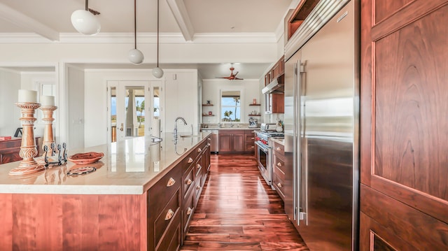 kitchen featuring high end appliances, dark wood-type flooring, ornamental molding, and a sink