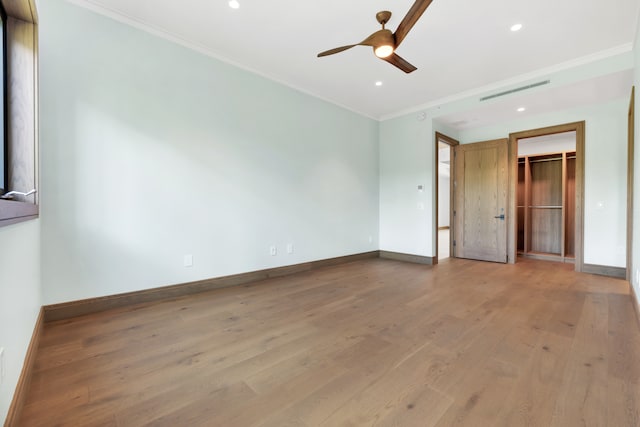 interior space with crown molding, wood-type flooring, a spacious closet, a closet, and ceiling fan