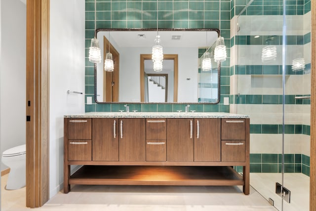 bathroom with tile walls, a shower with shower door, vanity, tile patterned flooring, and toilet