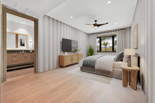 bedroom featuring ceiling fan, light hardwood / wood-style floors, and ensuite bathroom