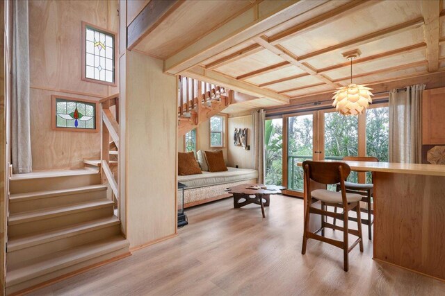 kitchen featuring coffered ceiling, wooden walls, beam ceiling, light hardwood / wood-style flooring, and stainless steel refrigerator