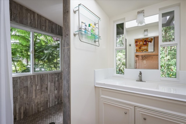 bathroom featuring tiled shower, vanity, and a healthy amount of sunlight