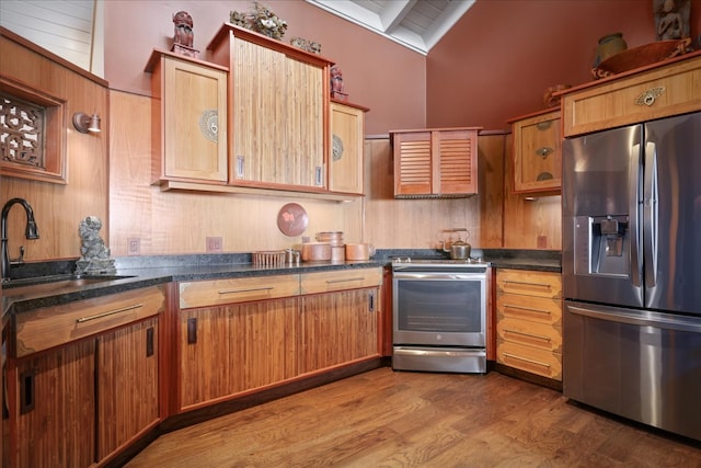 kitchen featuring hardwood / wood-style floors, lofted ceiling, stainless steel fridge, stove, and sink