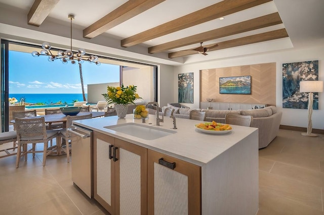 kitchen with an island with sink, sink, decorative light fixtures, ceiling fan with notable chandelier, and a water view