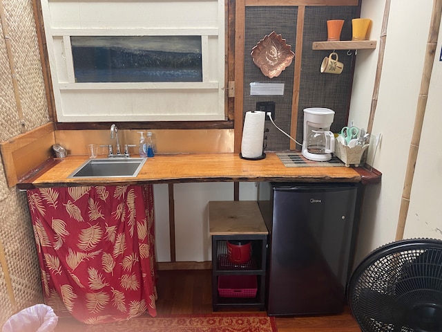 kitchen with sink, hardwood / wood-style floors, fridge, and a fireplace