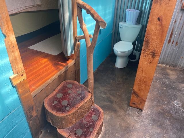 bathroom with toilet and concrete flooring