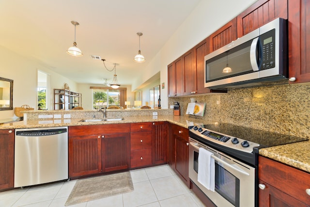 kitchen featuring sink, stainless steel appliances, light stone counters, tasteful backsplash, and kitchen peninsula