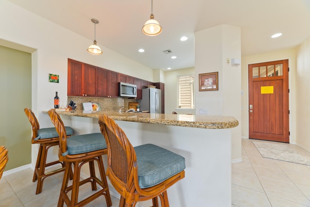 kitchen with decorative light fixtures, a breakfast bar area, stainless steel appliances, and kitchen peninsula