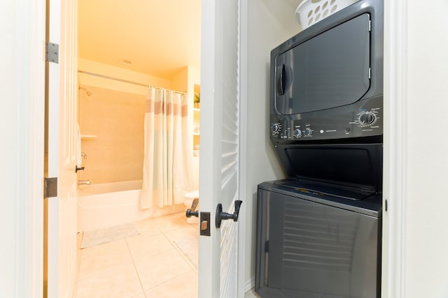 clothes washing area with light tile patterned flooring and stacked washing maching and dryer