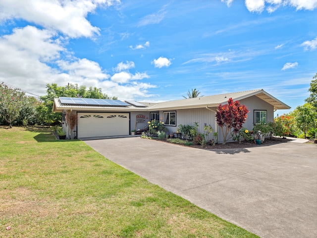 ranch-style house featuring a garage, a front lawn, and solar panels