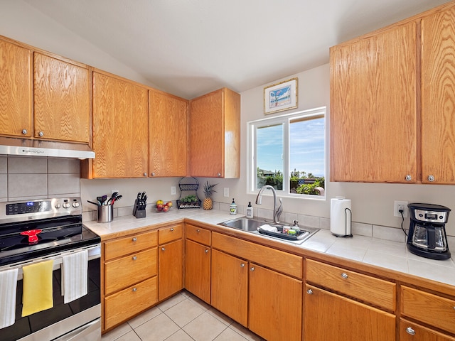 kitchen with tasteful backsplash, sink, tile countertops, light tile patterned flooring, and stainless steel range with electric stovetop