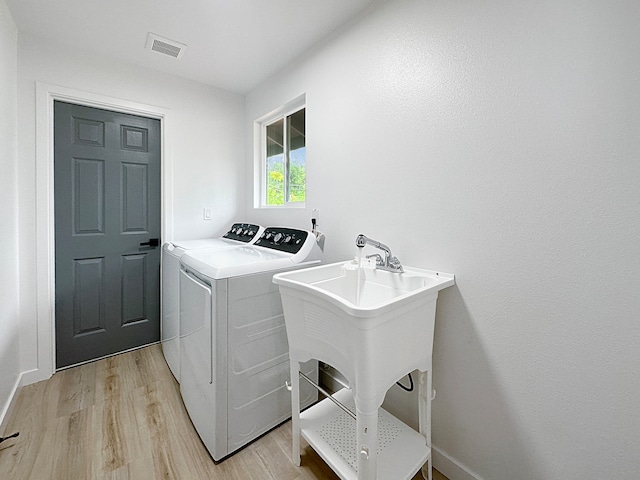 clothes washing area featuring light hardwood / wood-style flooring and washer and clothes dryer