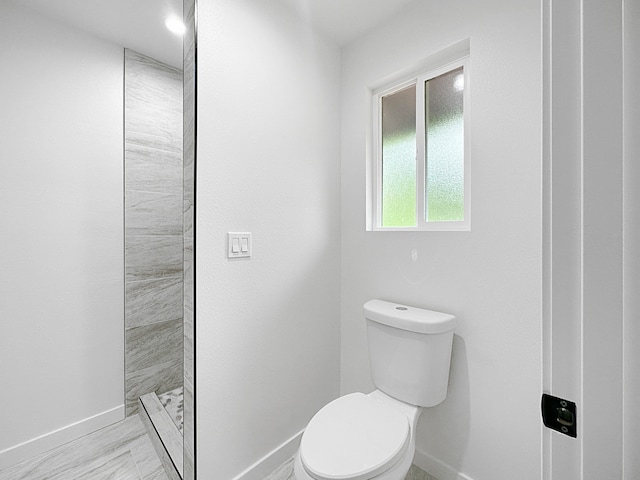 bathroom featuring tiled shower and toilet