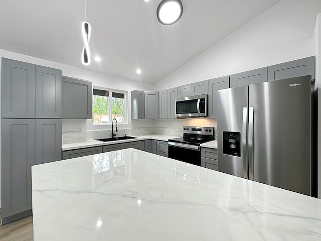 kitchen with stainless steel appliances, sink, gray cabinets, lofted ceiling, and light stone counters