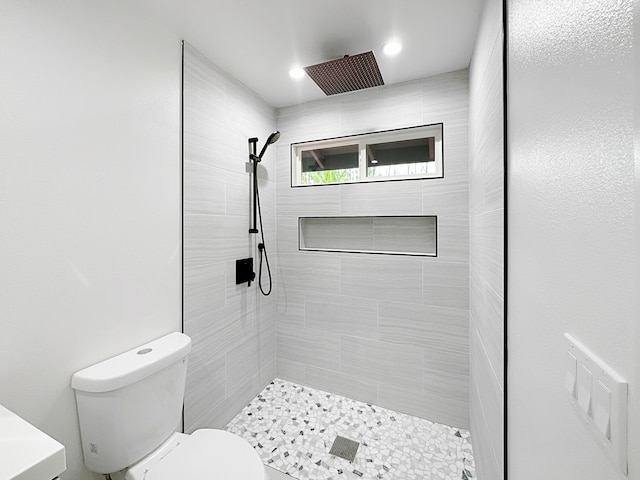 bathroom featuring toilet and a tile shower