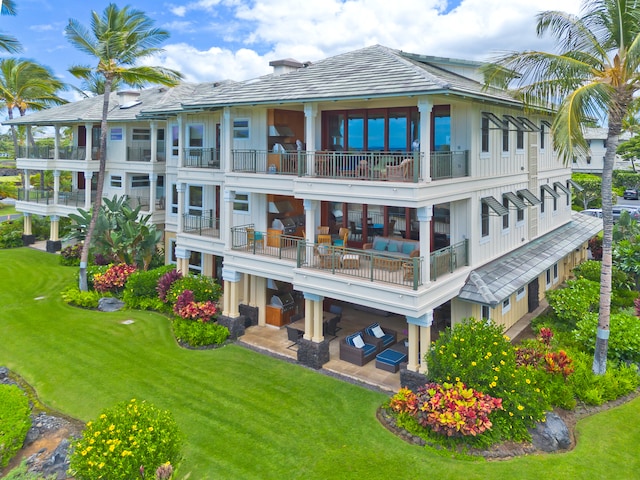 back of house with a balcony and a yard