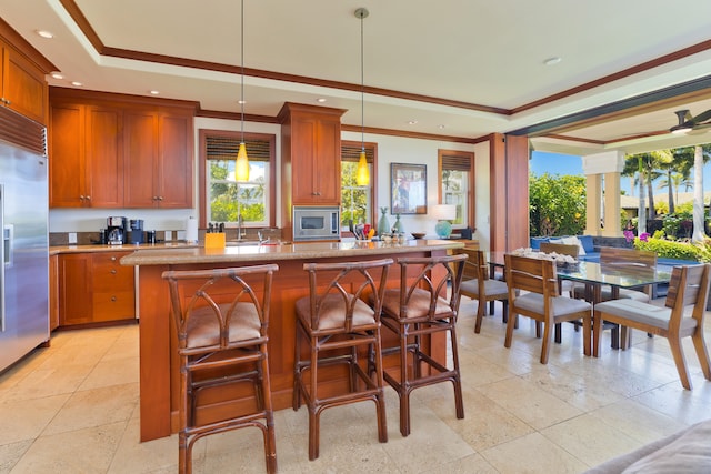 kitchen featuring decorative light fixtures, a kitchen bar, crown molding, light tile patterned flooring, and built in appliances