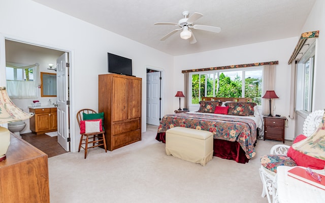 bedroom featuring light carpet, a textured ceiling, ensuite bath, and ceiling fan