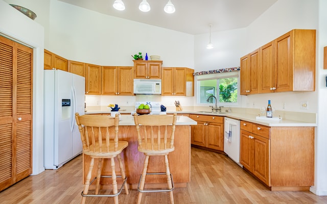 kitchen with light hardwood / wood-style floors, sink, white appliances, and a center island