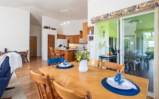 dining area with light hardwood / wood-style floors and high vaulted ceiling