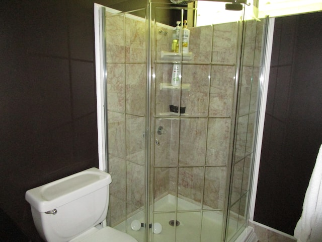 bathroom featuring a shower with shower door and toilet