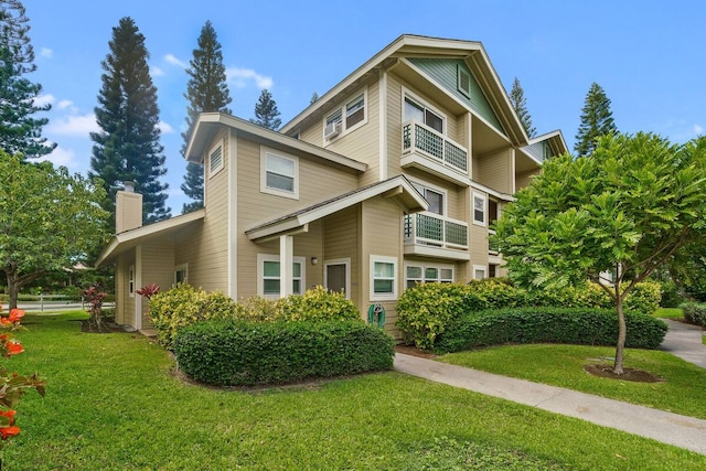 view of front of house featuring a balcony and a front lawn