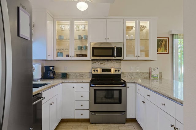 kitchen with white cabinetry, light tile patterned floors, stainless steel appliances, and light stone countertops