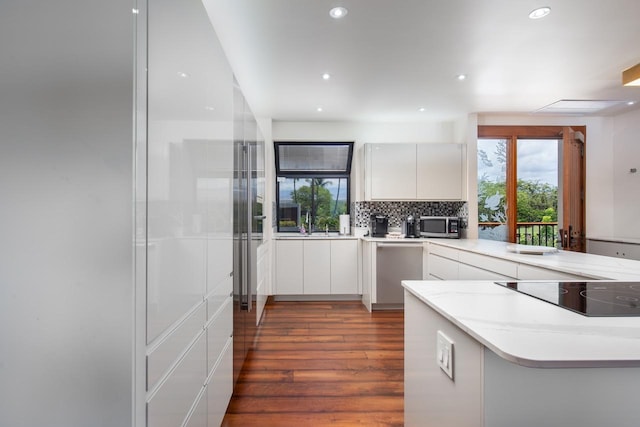 kitchen with decorative backsplash, modern cabinets, wood finished floors, stainless steel appliances, and white cabinetry