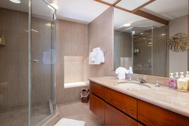 bathroom featuring tile patterned floors, a shower stall, vanity, and tile walls