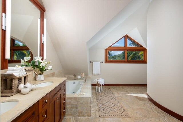 bathroom featuring tile patterned floors, tiled bath, a healthy amount of sunlight, and double sink vanity